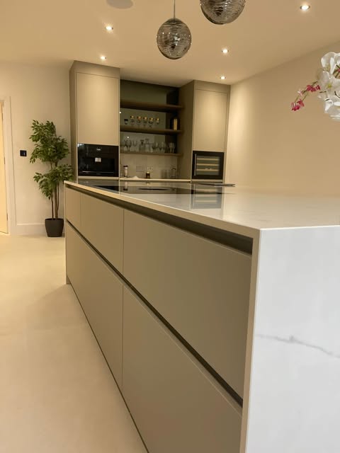 Contemporary kitchen with a handleless island, pale worktop and sculptural pendant lights